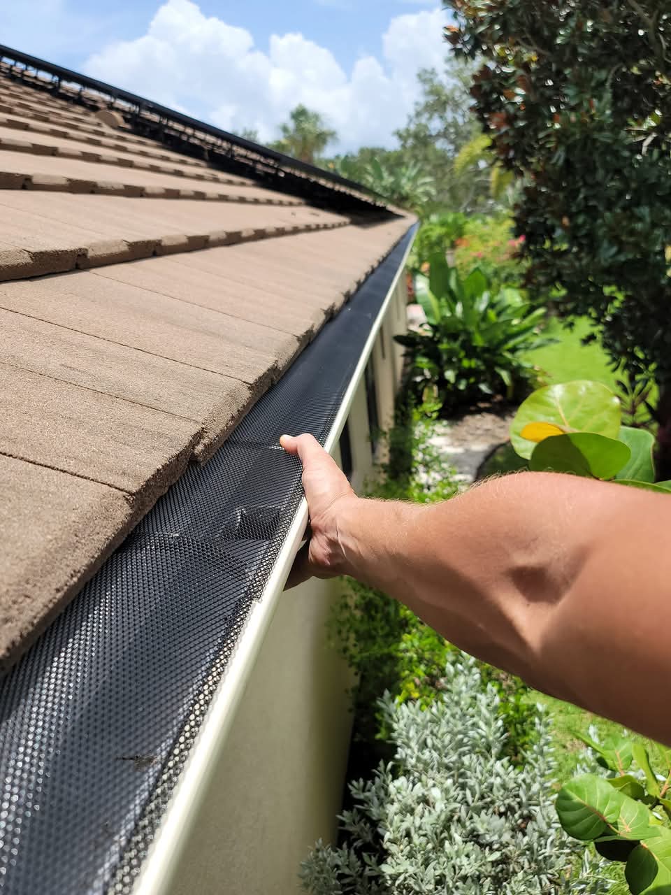 Eli inspecting an installed leaf guard on a seamless gutter — professional debris protection for your home