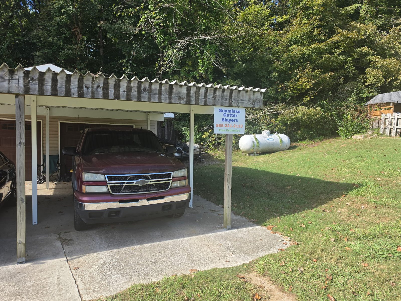 Seamless Gutter Slayers sign with the phone number 865-221-2133 beside a work truck.