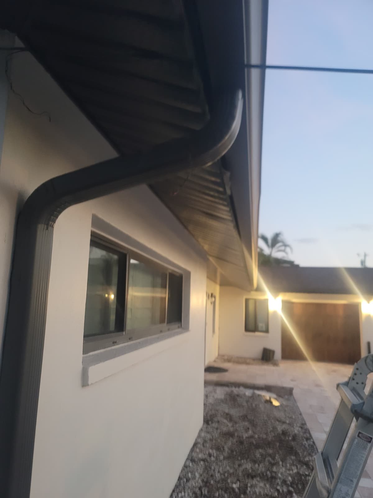 Black seamless gutter with a matching downspout.