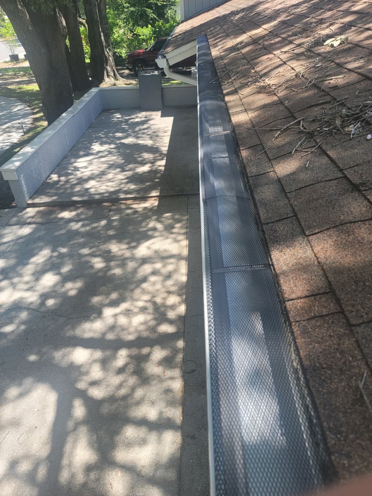 Seamless gutter with a mesh leaf guard along a shingle roof edge.