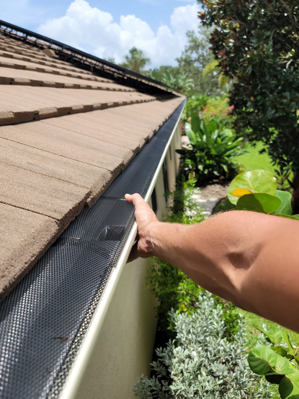 Seamless gutter with a leaf guard installed along a tile roof