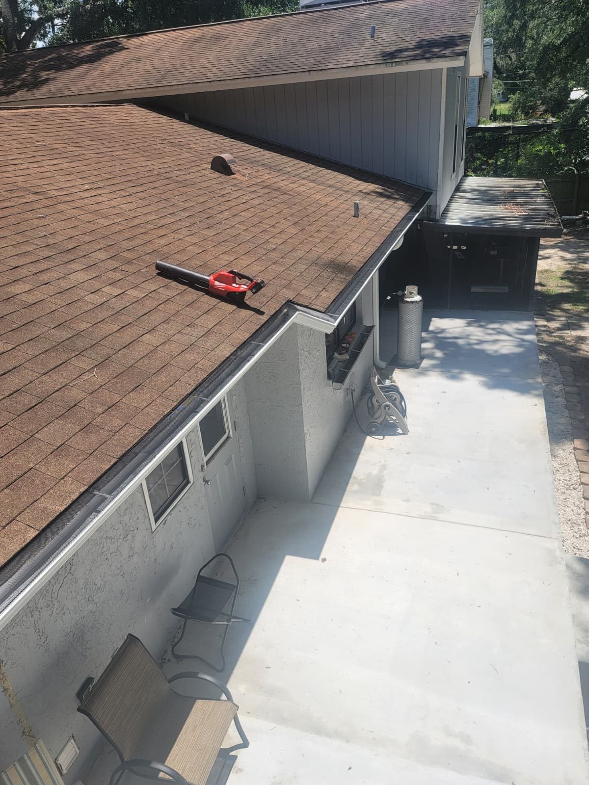 Seamless gutter running along a shingle roof edge.