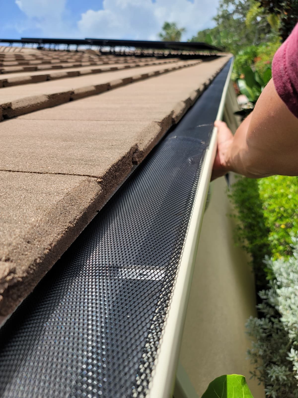 A new gutter sitting snug under the roof edge with no gap behind it.