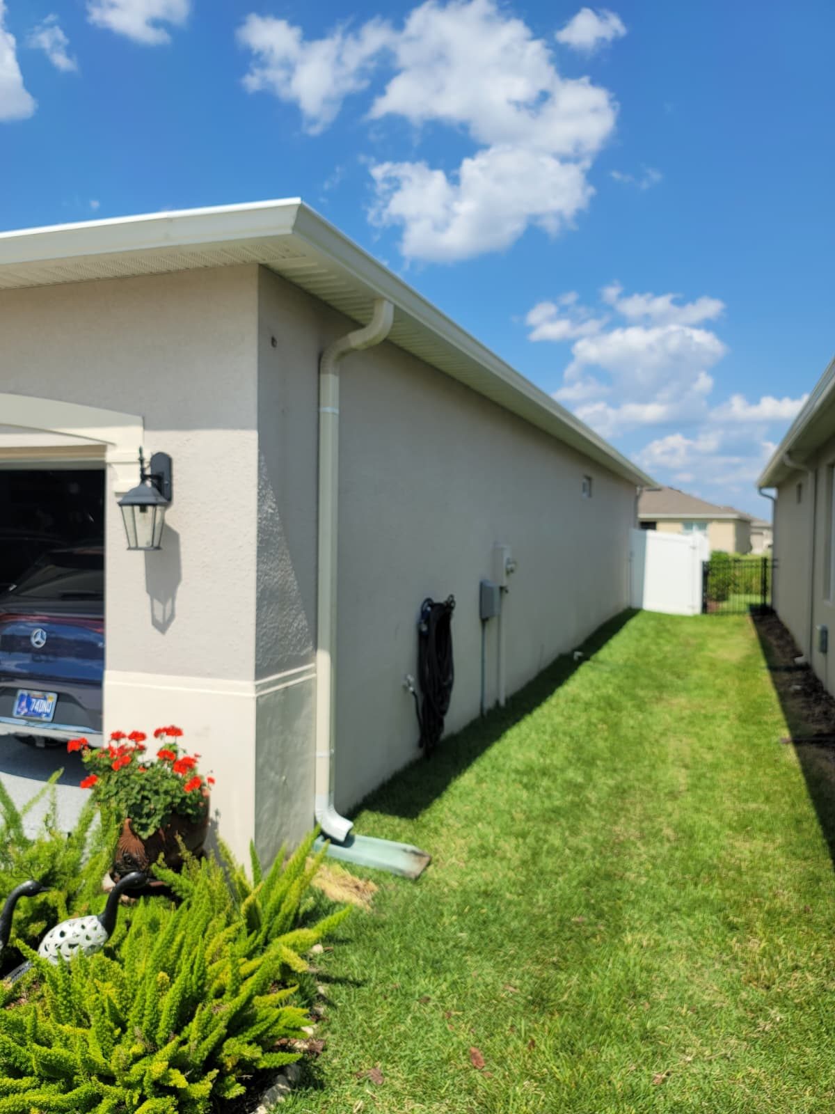 White downspout fastened to a stucco wall.